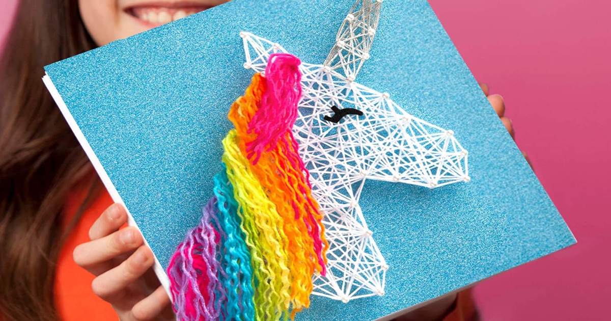 a girl holding her DIY string art. It is of a unicorn