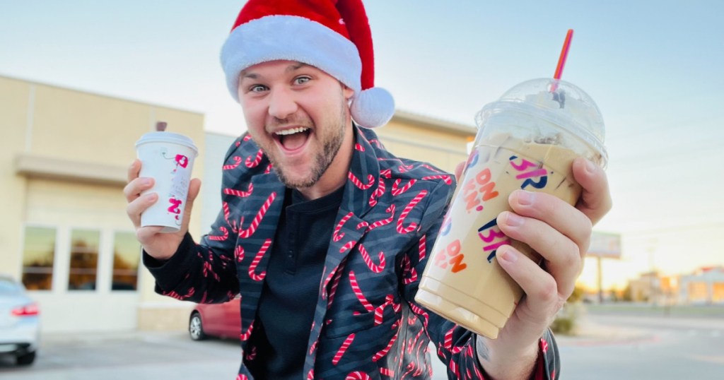 man in Santa hat holding 2 Dunkin coffees