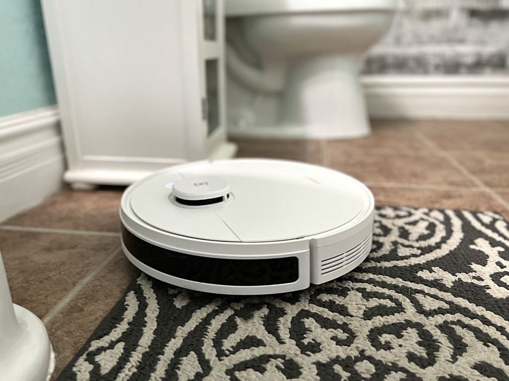 white robot vacuum on rug in bathroom