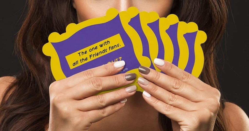 woman holding friends trivia game cards