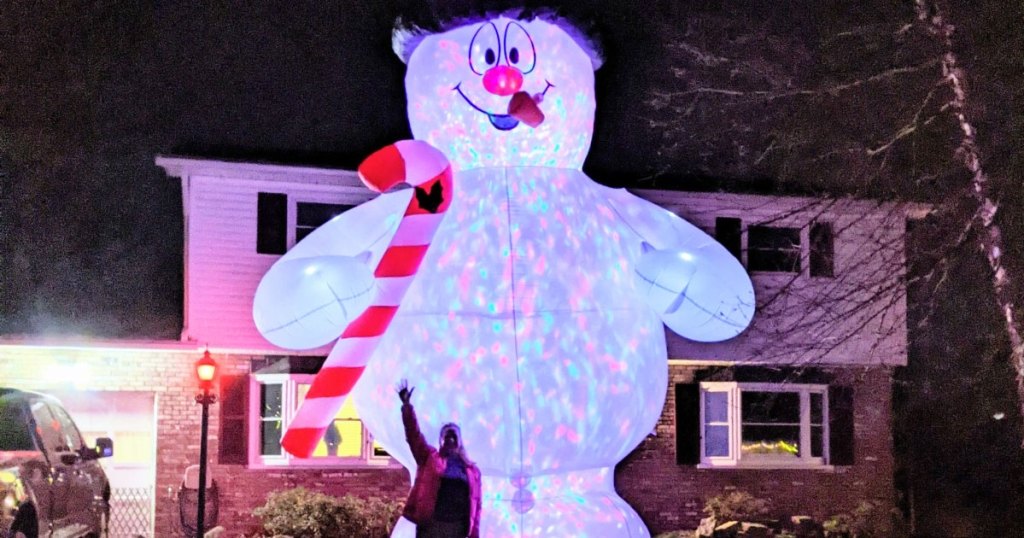 woman standing in front of large snowman inflatable