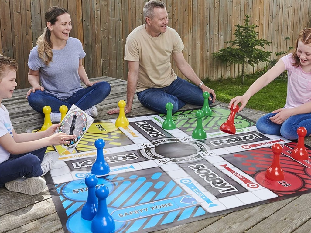 Family outstide on a wooden porch, playing a Giant Sorry! Board Game