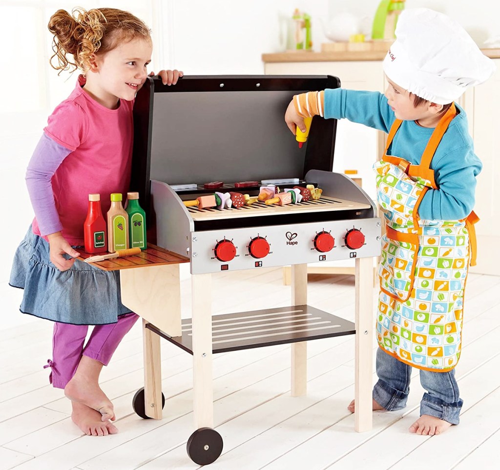 two kids standing next to play grill