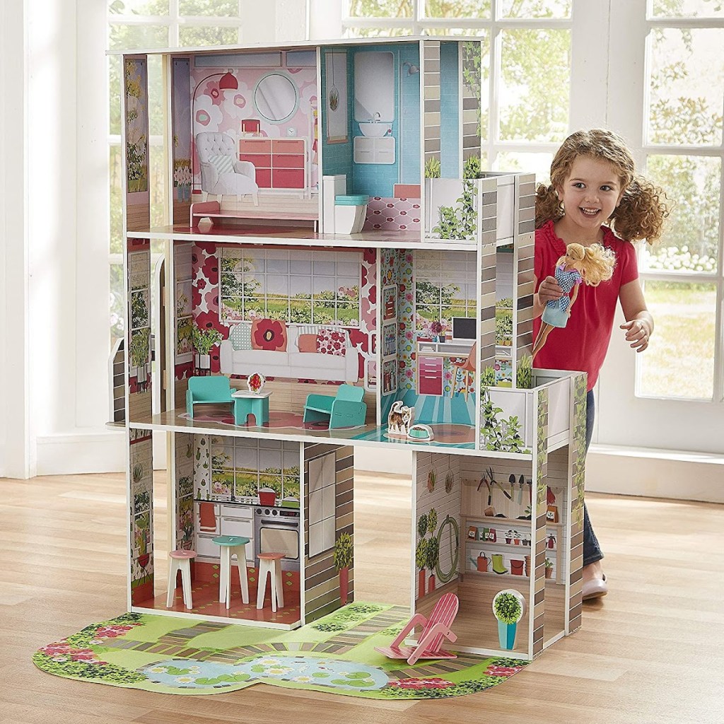 girl standing next to a large dollhouse