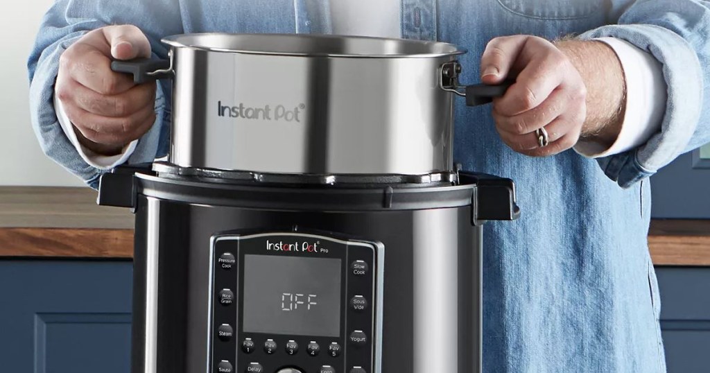 arms pulling out a pot from a small kitchen appliance