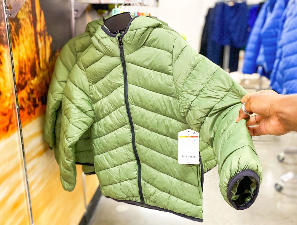 holding green puffer jacket in store