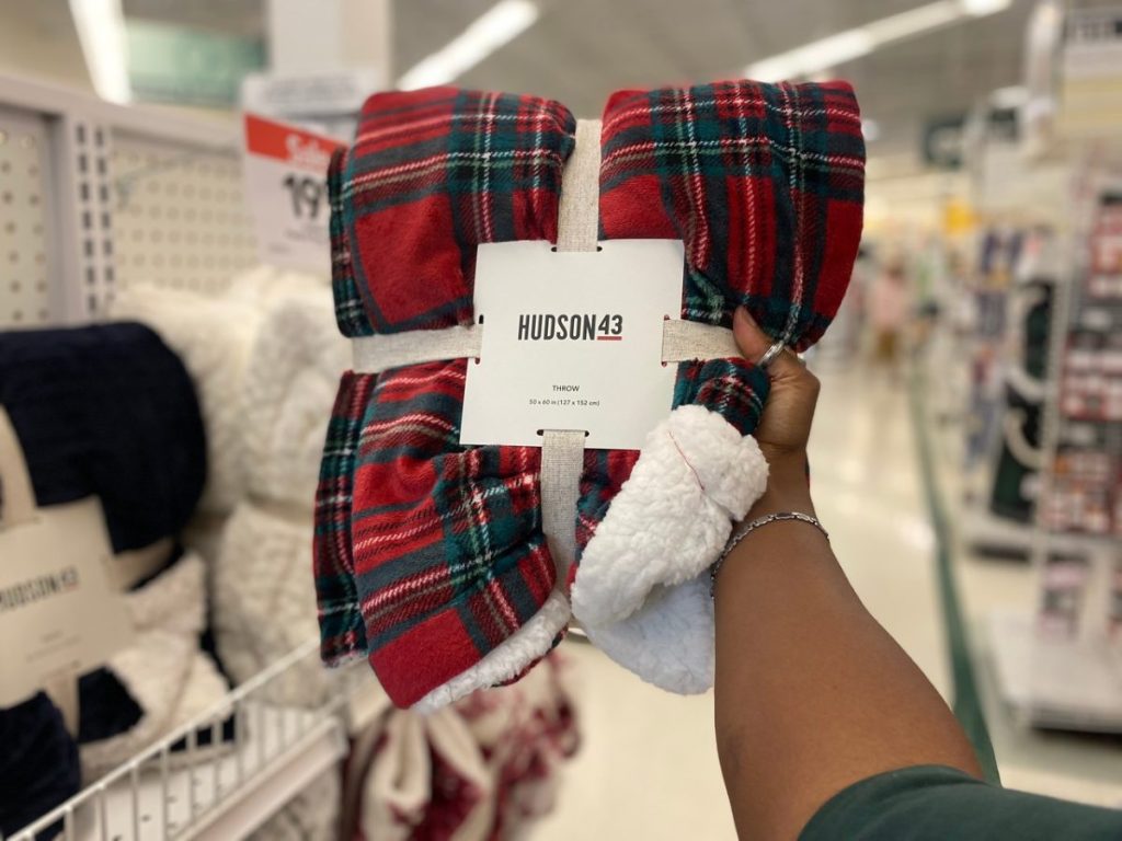 hand holding a red plaid blanket in store aisle