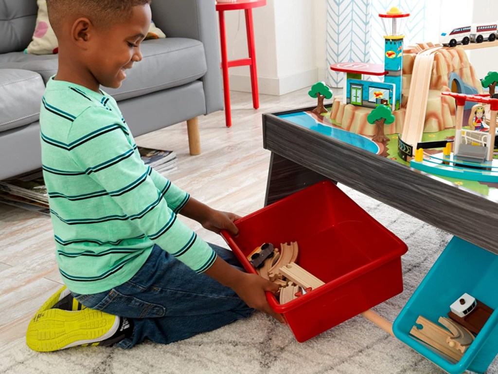 boy playing with train table set in living room
