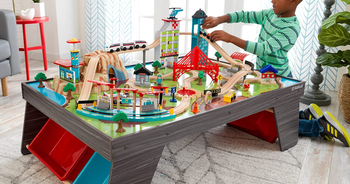 boy playing with train table set in living room
