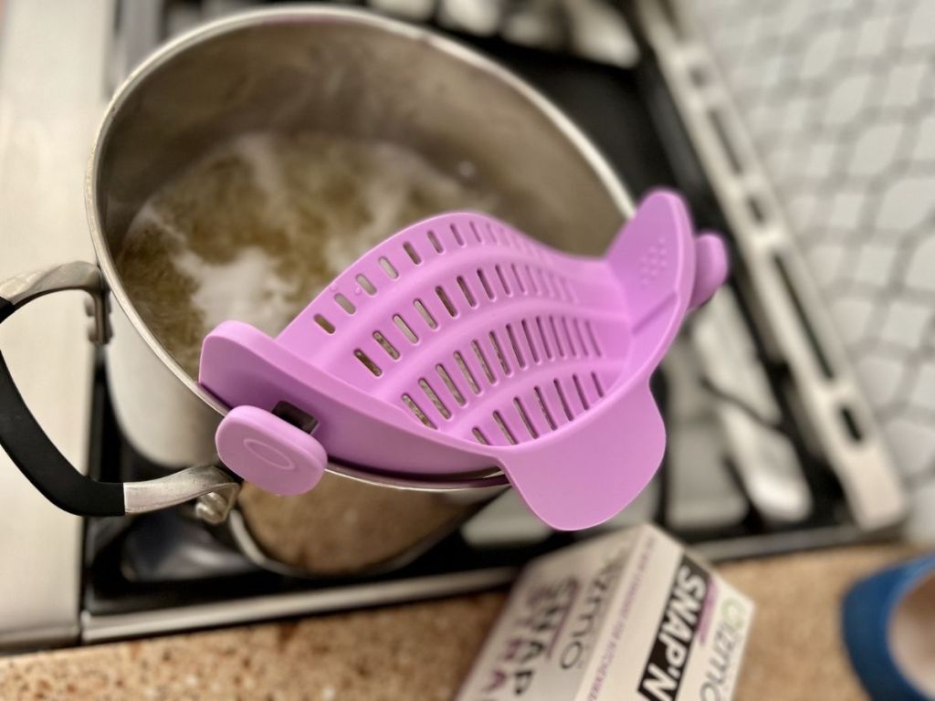 woman with a pot of noodles and purple strainer
