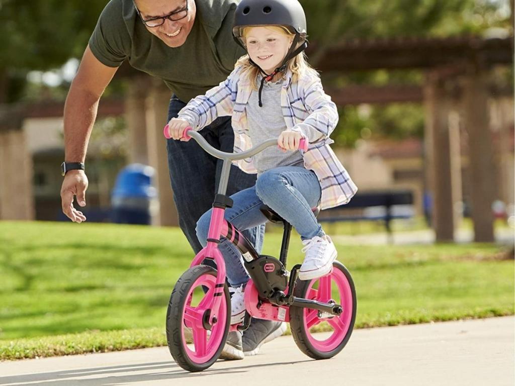 girl riding little tikes balance to pedal bike with dad helping