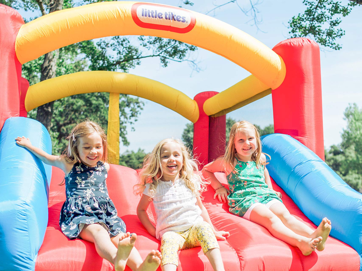 three girls coming down slide in inflatable bounce house