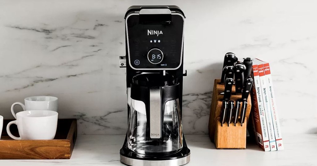 coffee maker on kitchen counter next to cups and knives