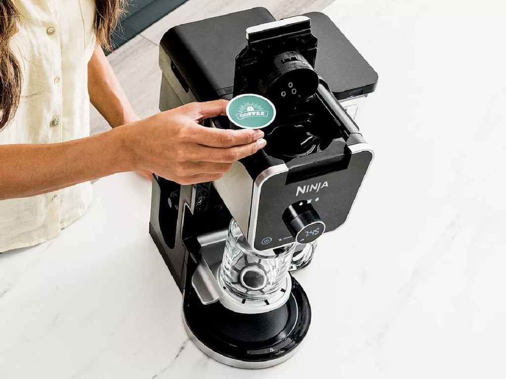 person putting pod into top of coffee maker