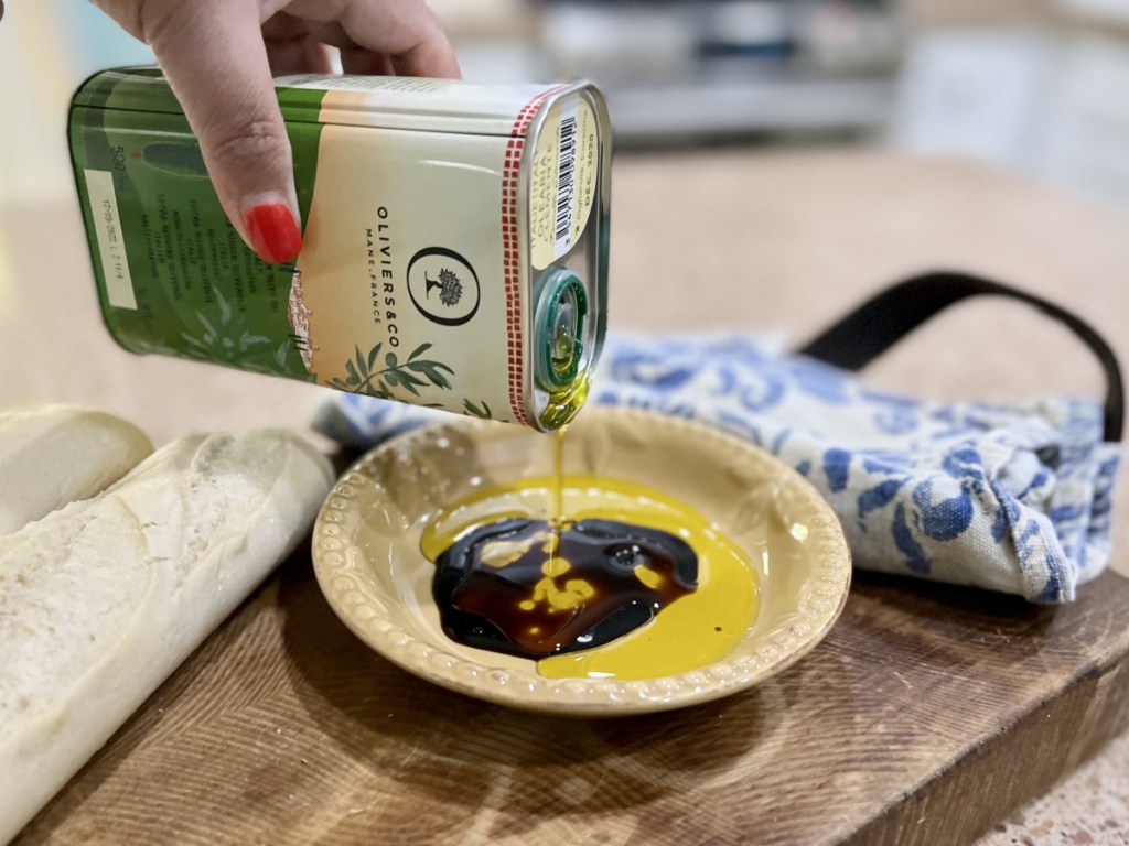 woman pouring Oliviers & Co. Extra Virgin Olive Oil into dish