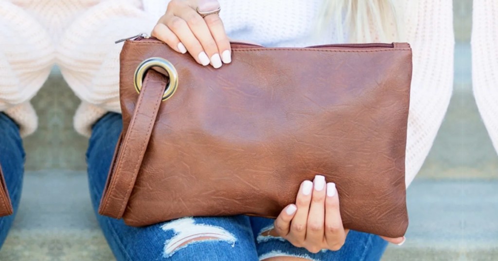 woman holding brown vegan leather oversized clutch