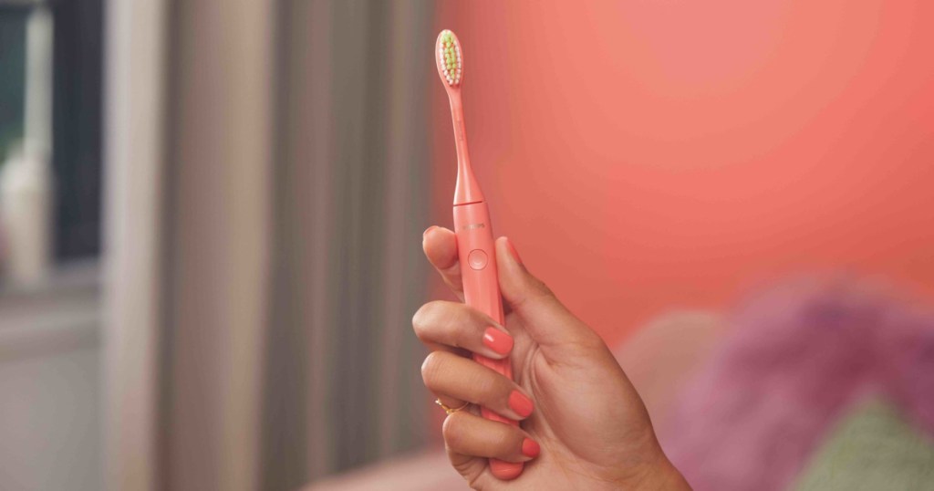 woman holding coral battery toothbrush