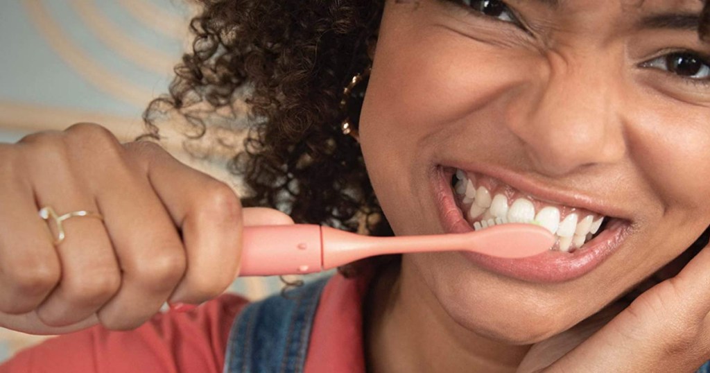 woman brushing teeth with coral battery toothbrush
