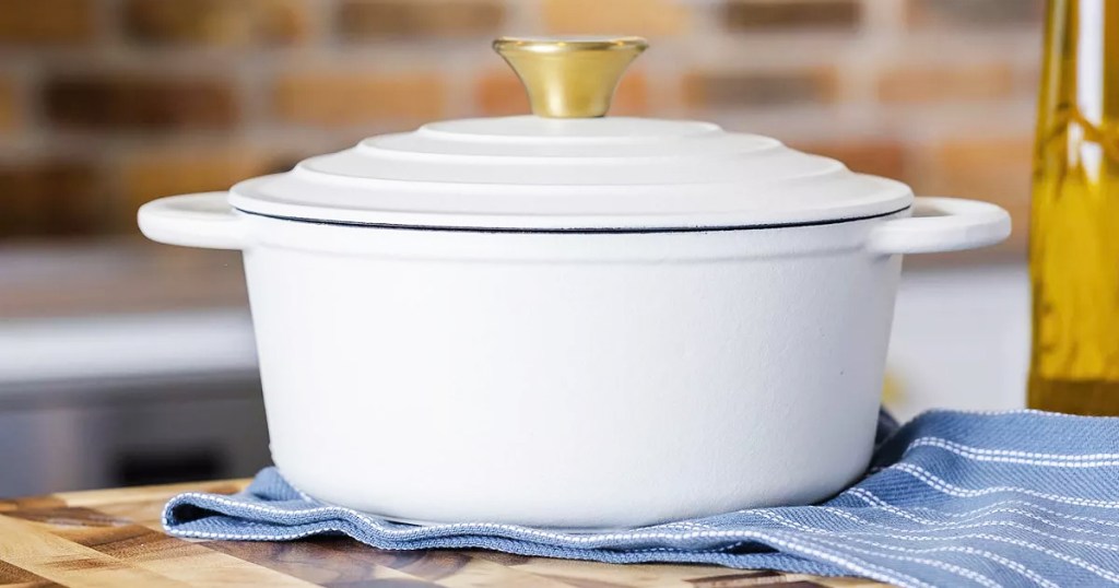 white dutch oven with lid on top of blue kitchen towel