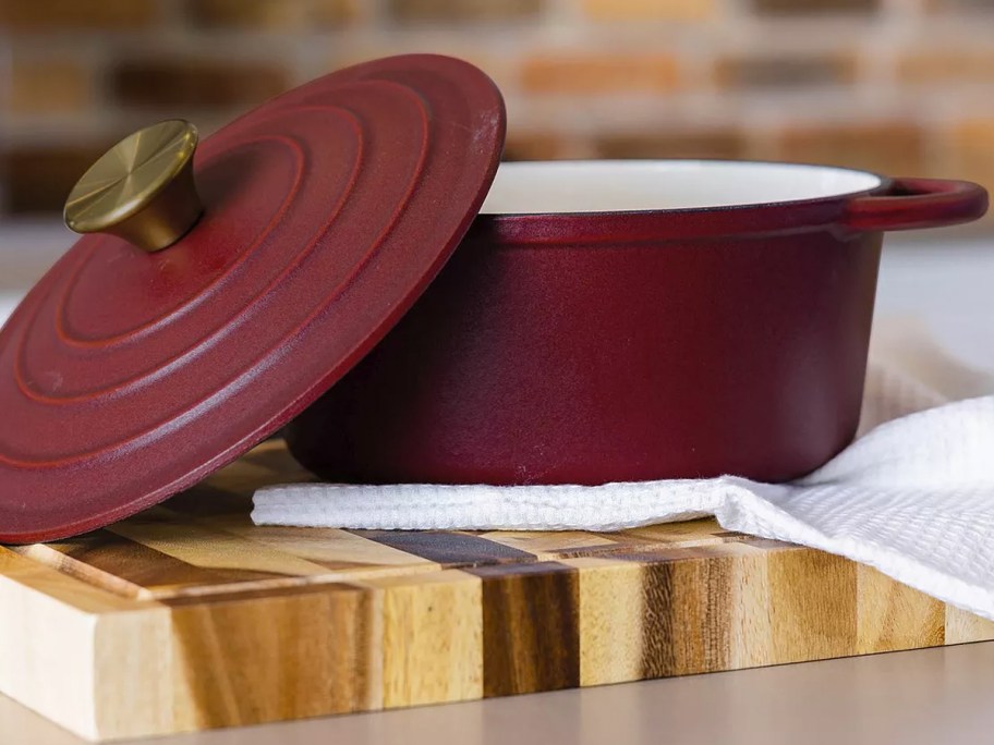 maroon dutch oven and lid on top of wood cutting board