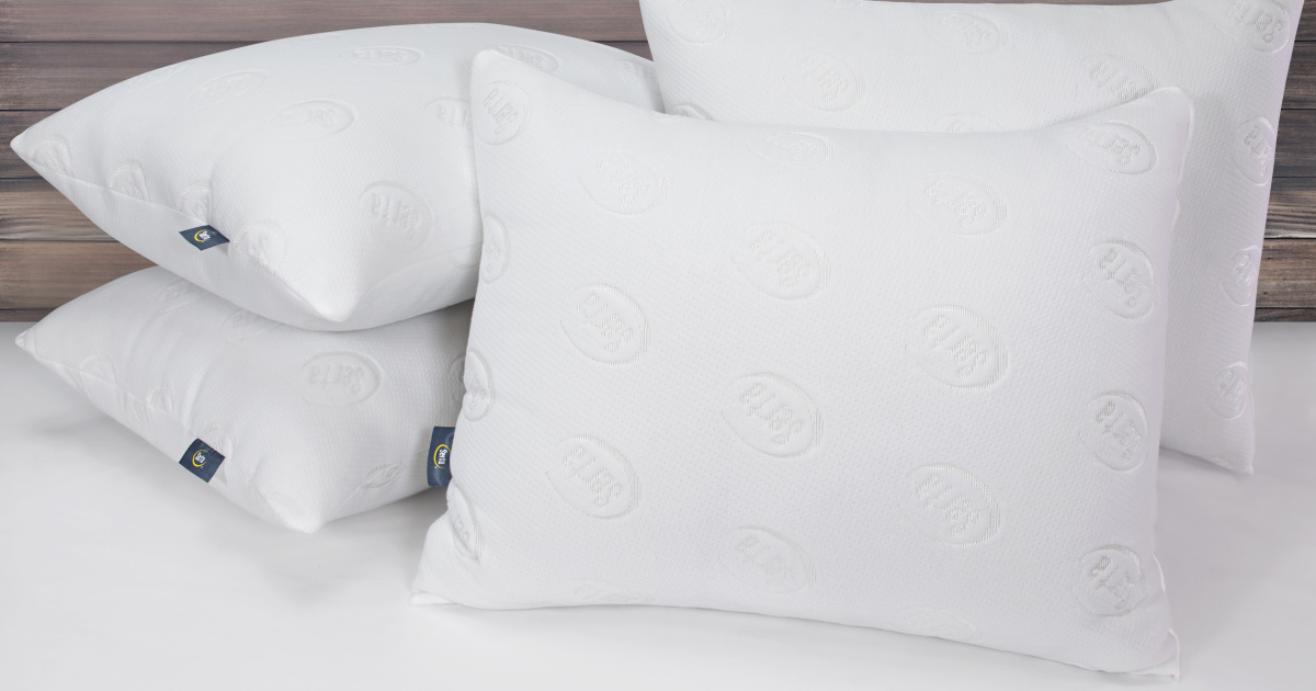 pile of four clean white pillows on a bed in front of a headboard
