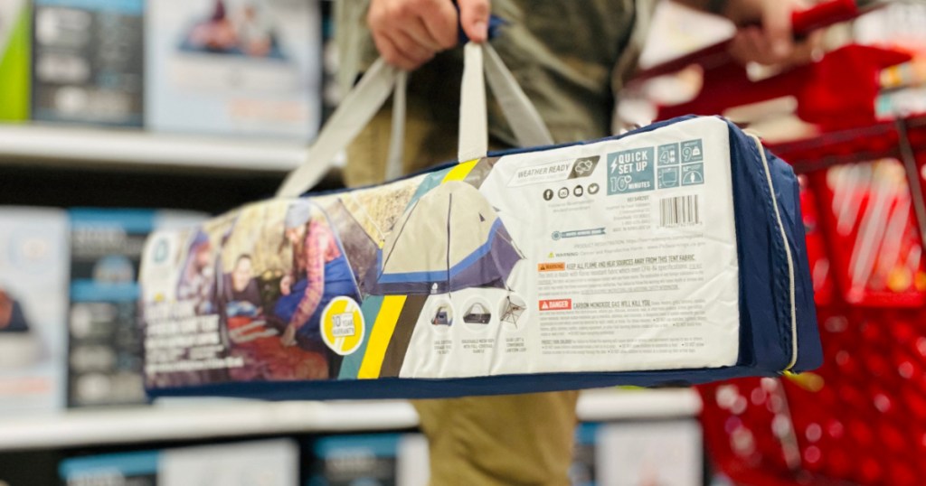 man carrying bag with blue tent inside 