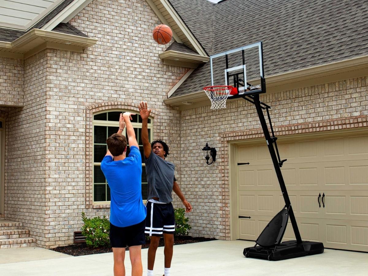 two boys playing basketball with spalding portable basketball hoop