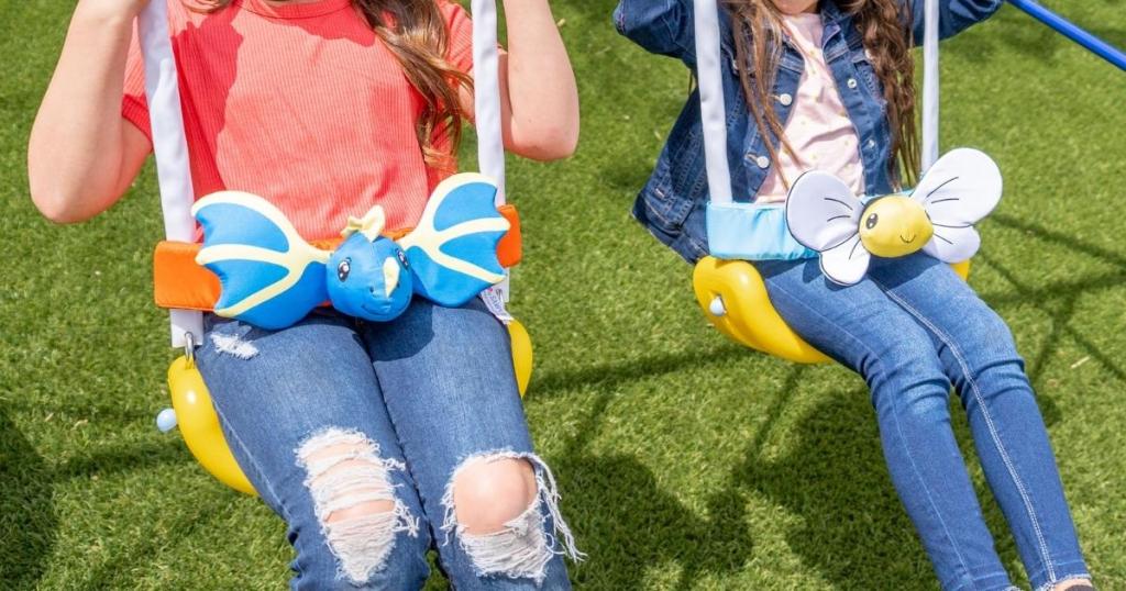 girls sitting on sportspower swing set with dragon and butterfly friends