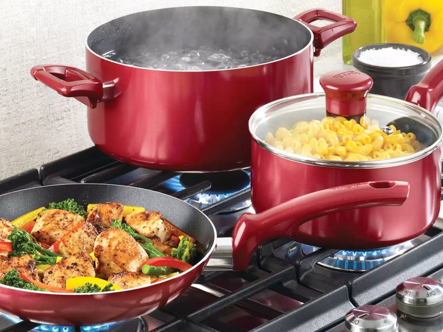 red pots and pans on stove with food in them