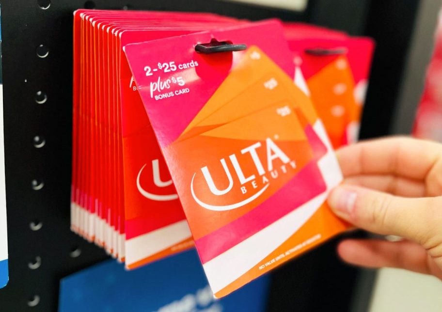 hand taking an ulta gift card from display at sams club