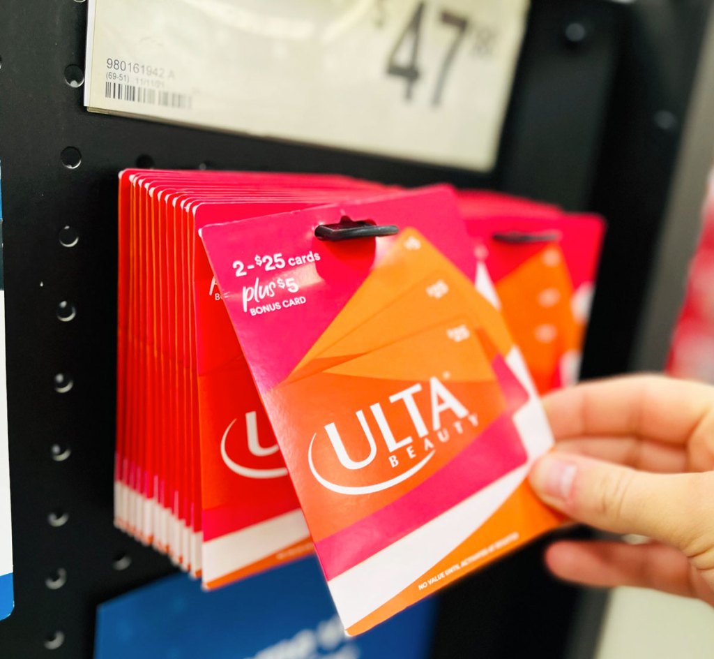 hand taking an ulta gift card from display at sams club