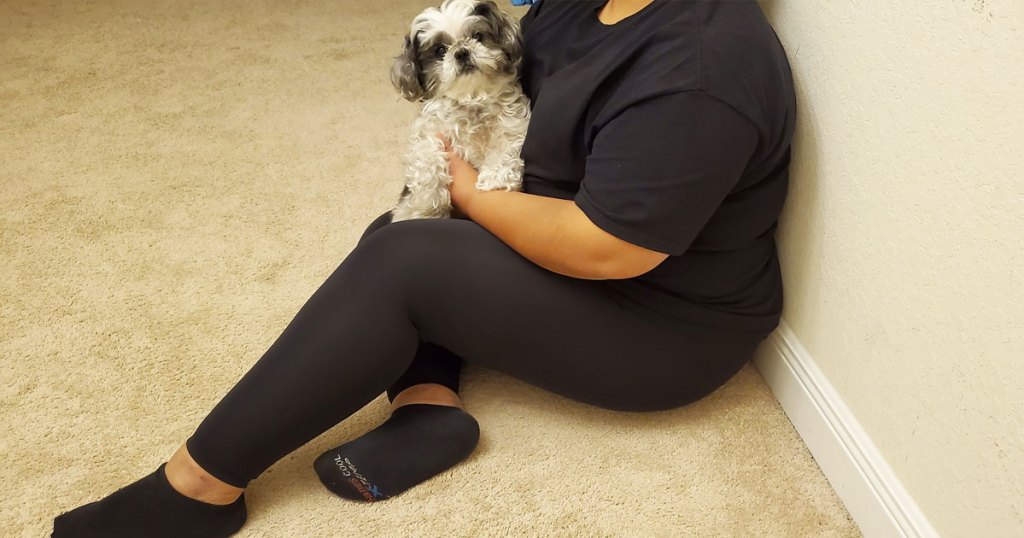 woman on floor holding dog in black outfit and leggings