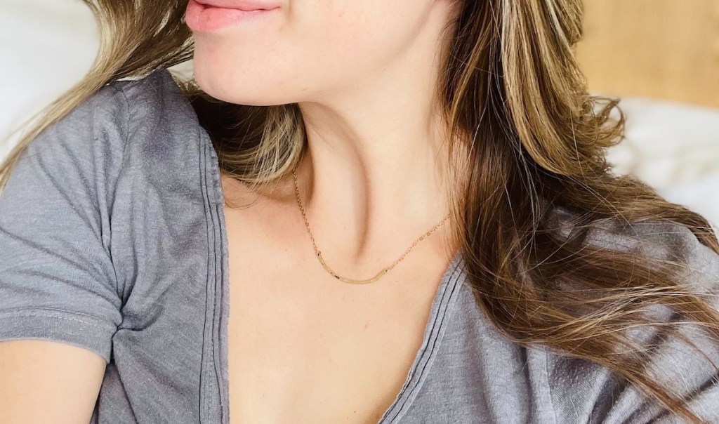 close up of gold bar necklace on woman