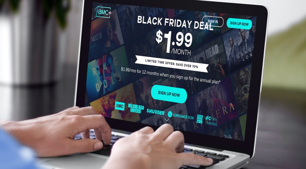 hands typing on laptap with amc+ black friday deal on screen