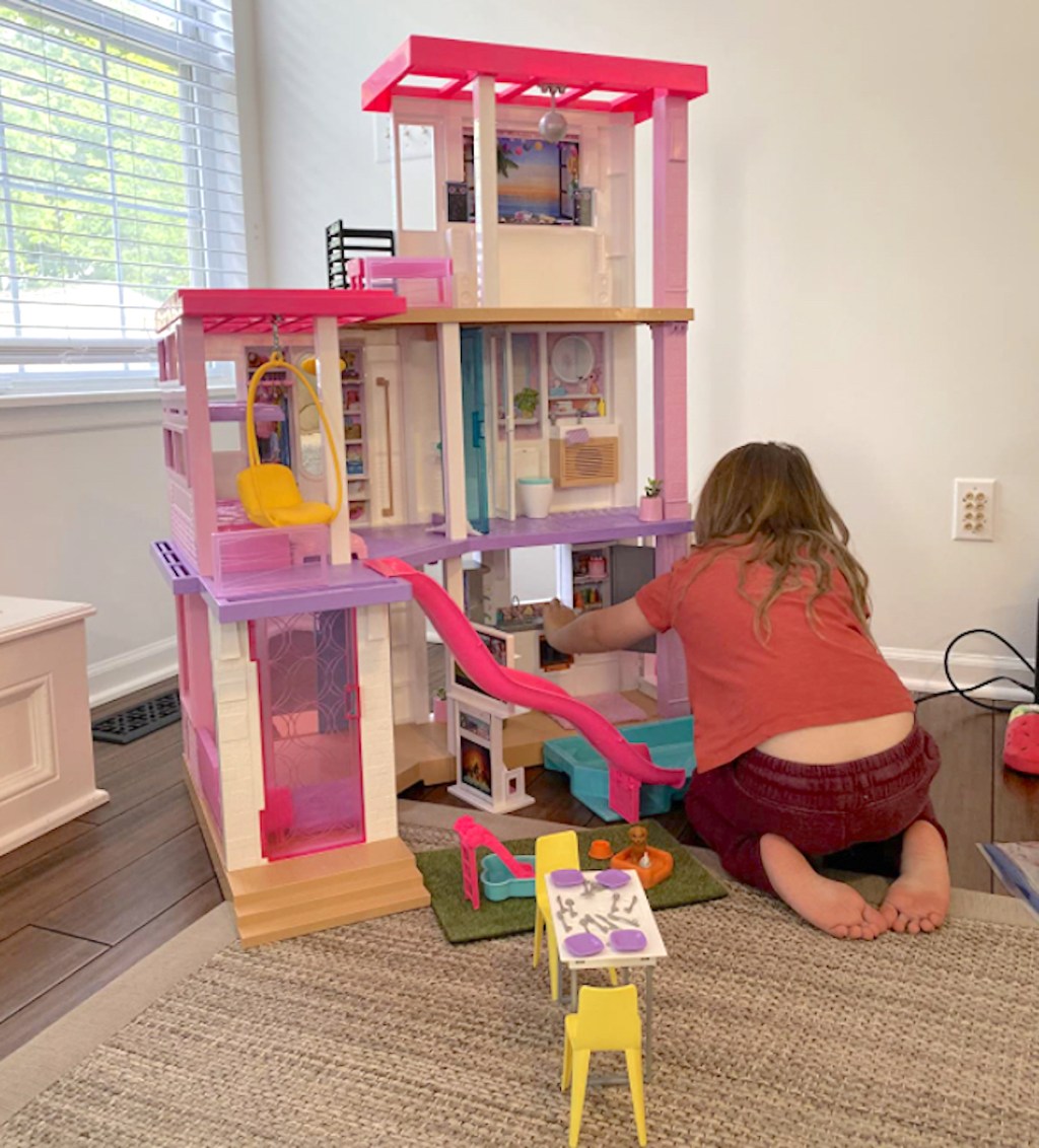 girl playing on floor with barbie dreamhouse