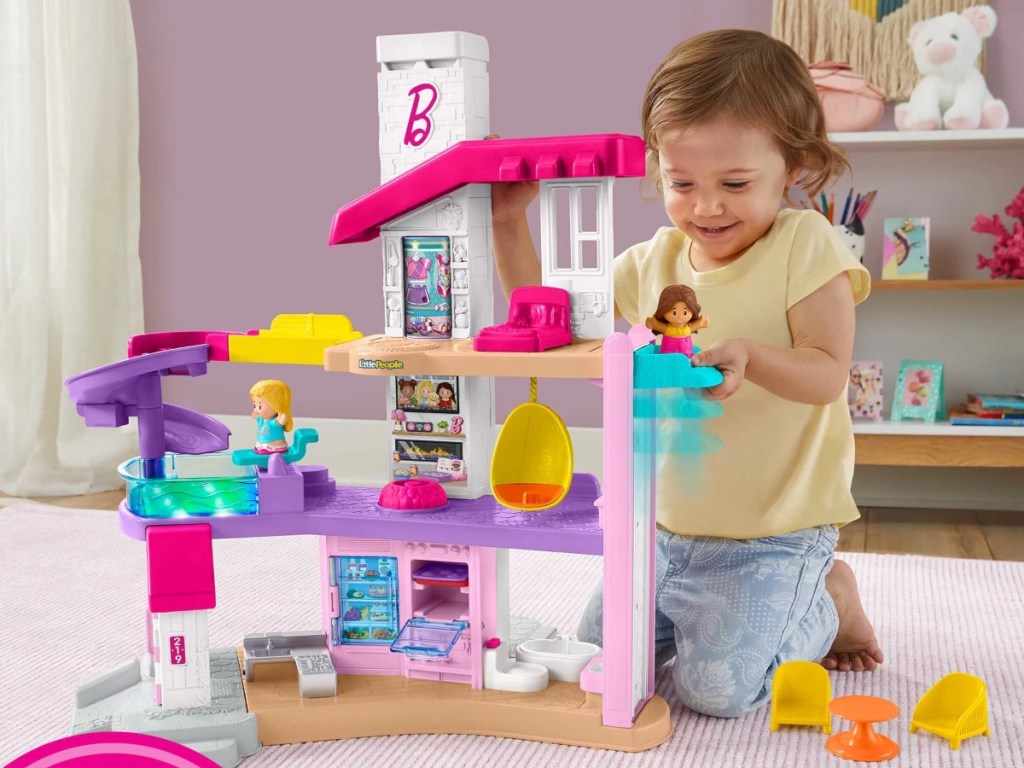 preschooler playing with Little People Barbie dreamhouse
