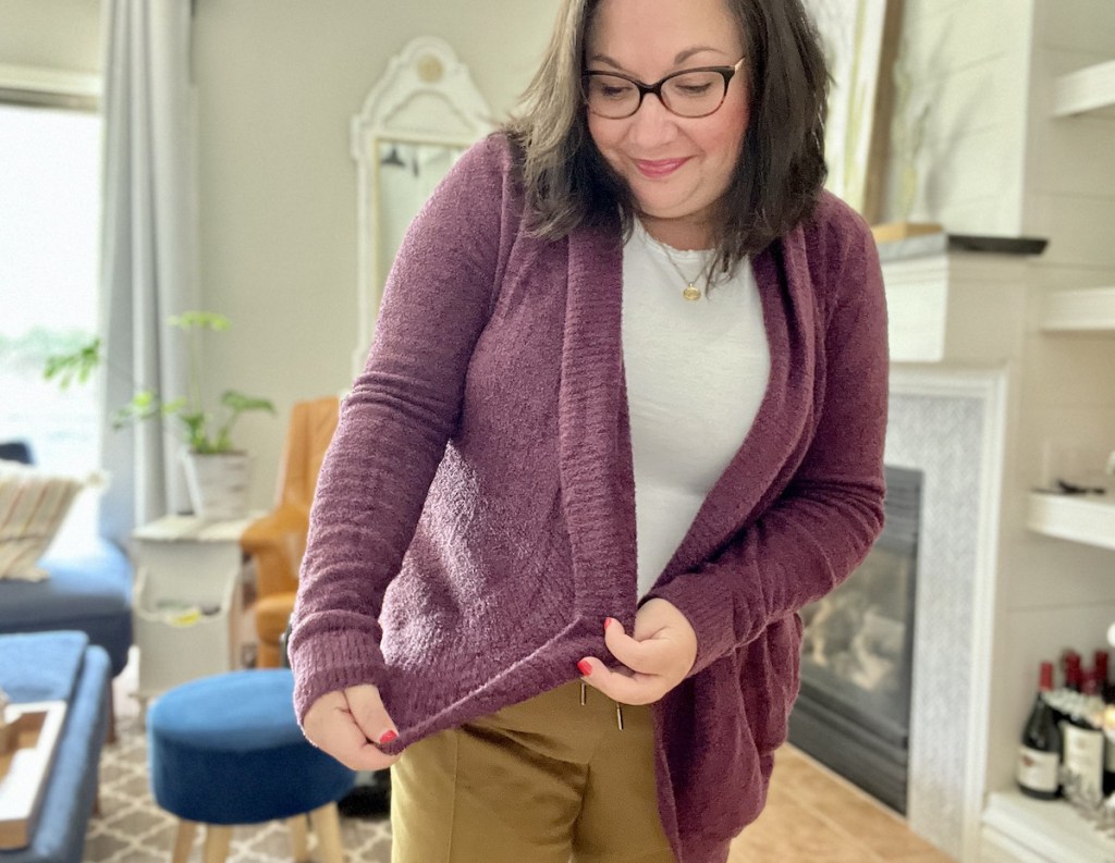 woman holding edge of purple cardigan standing in living room
