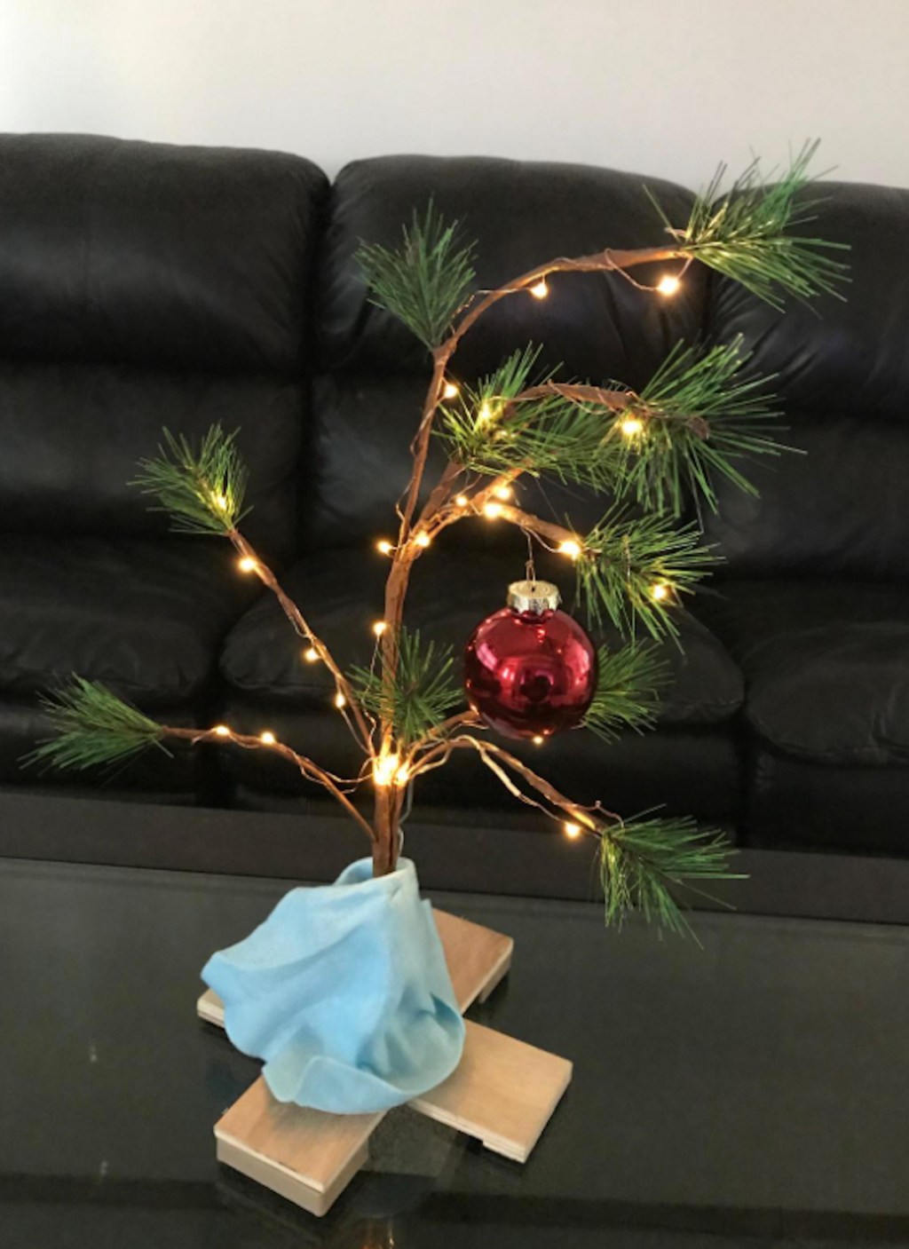 tiny mini charli brown tree with blue blanket and red ornament on coffee table