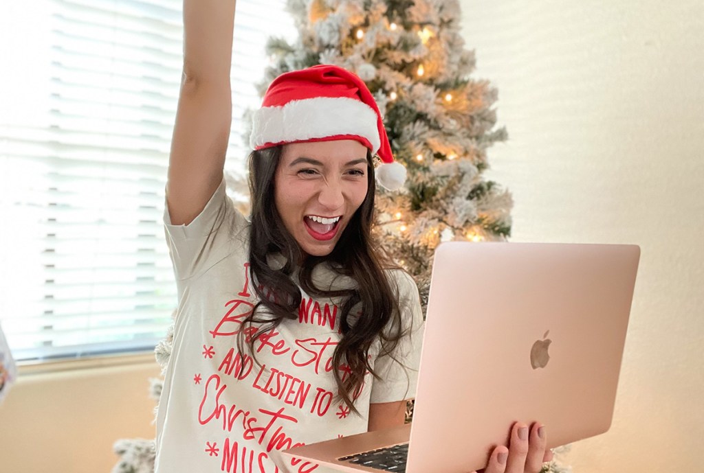 woman cheering at computer wearing holiday shirt