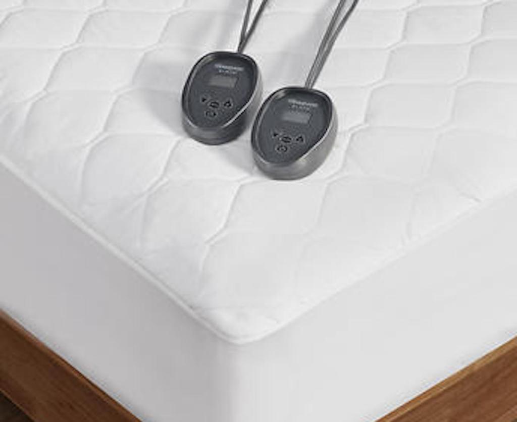 close up of white heating pad cover with two remotes