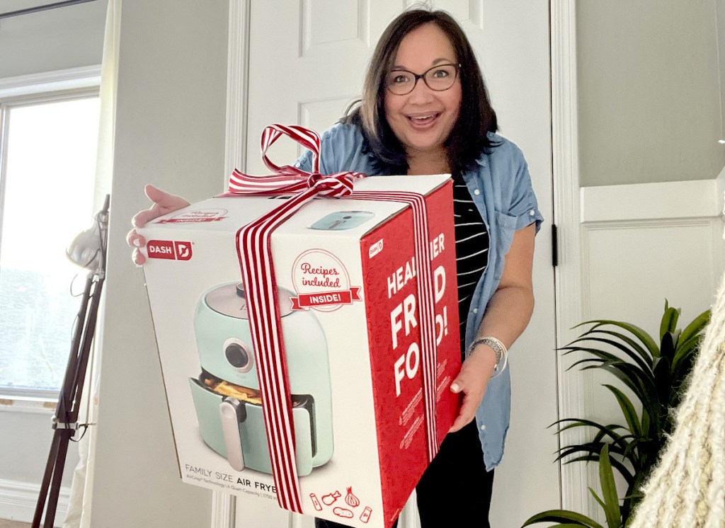 woman holding box with air fryer and christmas bow