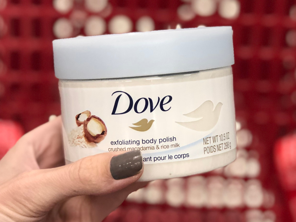 manicured hand holding tub of Dove brand body polish