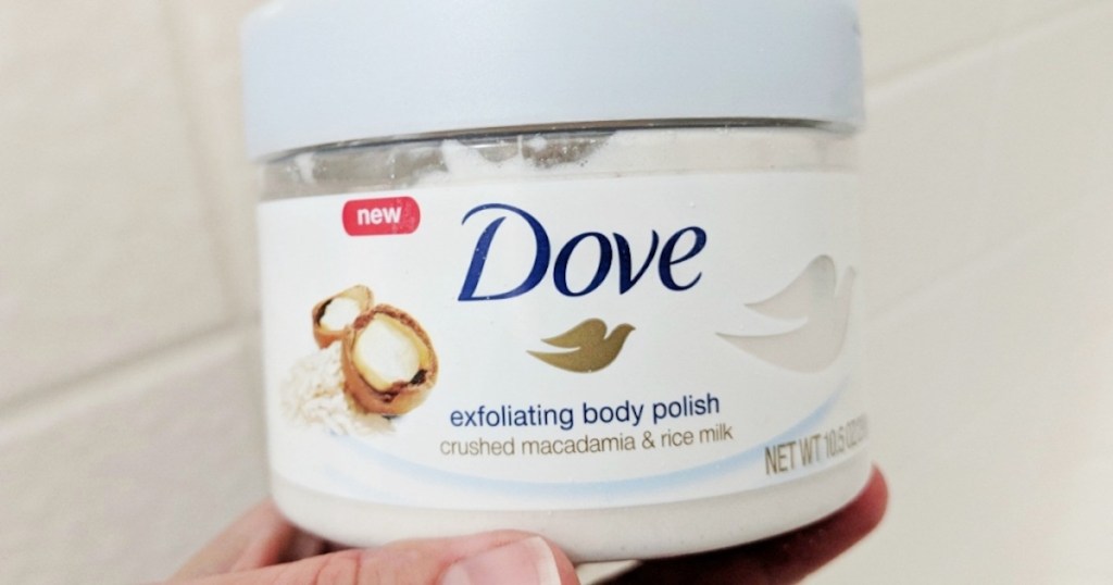 hand holding a tub of dove body scrub 