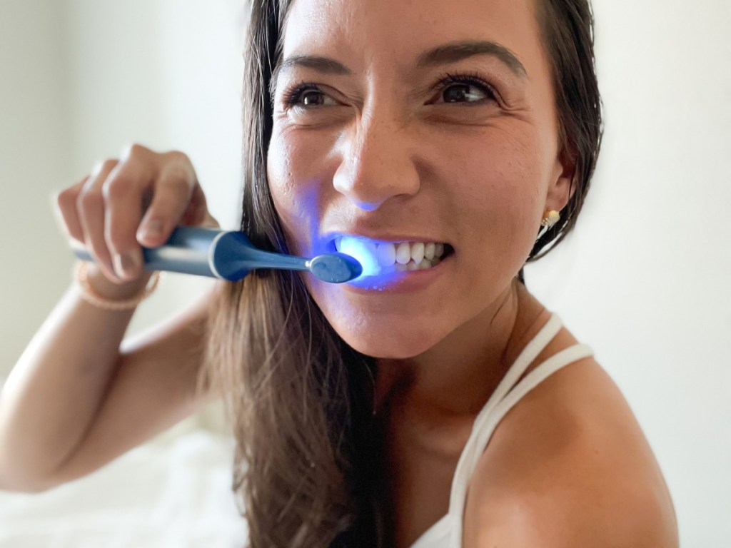 woman using electric toothbrush with LED light