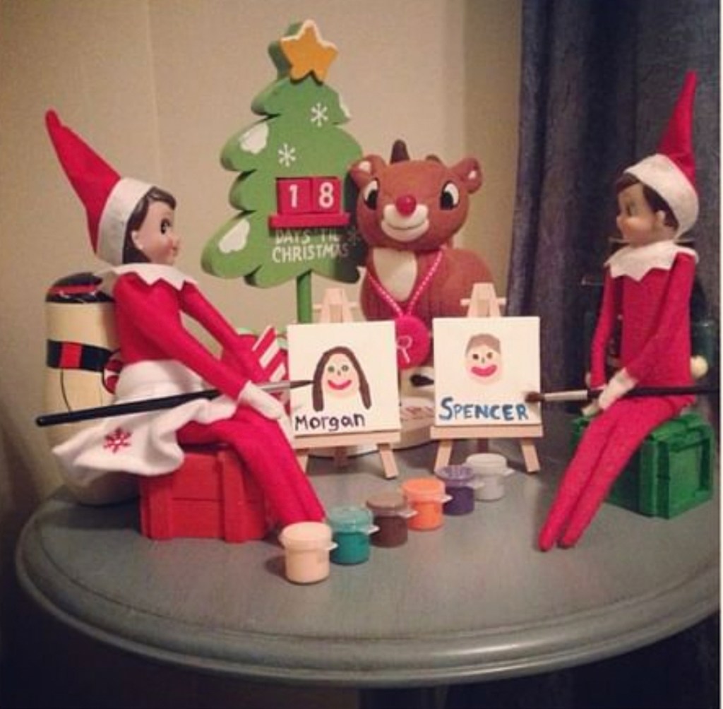 two elves sitting on table with mini art easels 
