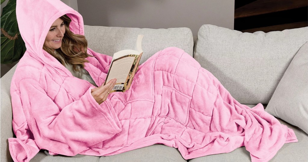 woman laying on a couch in a pink wearable blanket
