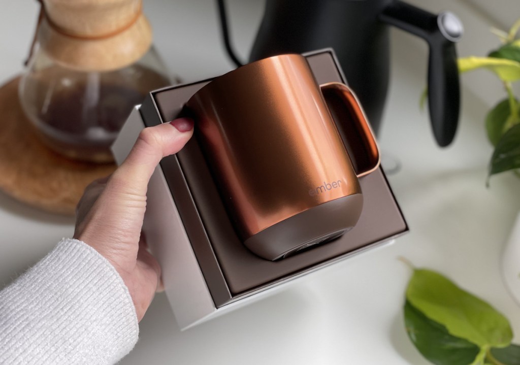 hand holding a box with copper colored coffee mug inside