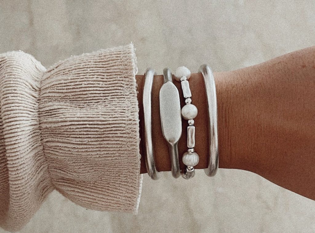 close up of arm with silver set of bracelets 