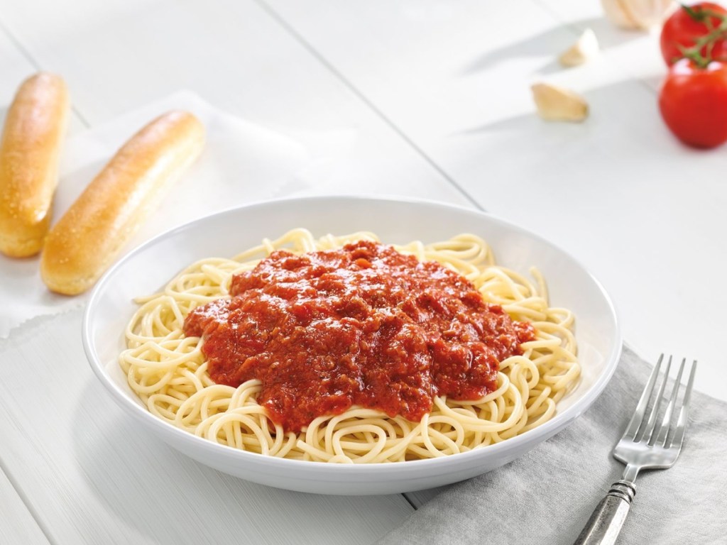 bowl of spaghetti with breadsticks