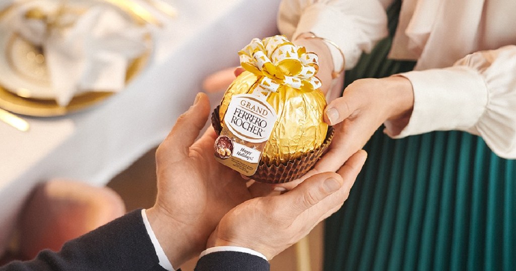 woman handing a gold wrapped candy package to a man